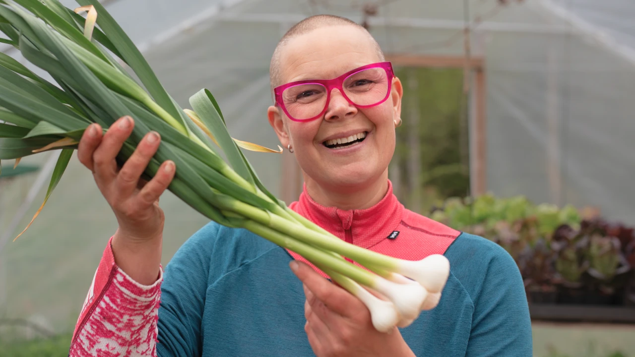 Sara Bäckmo tittar in i kameran och håller upp lökar