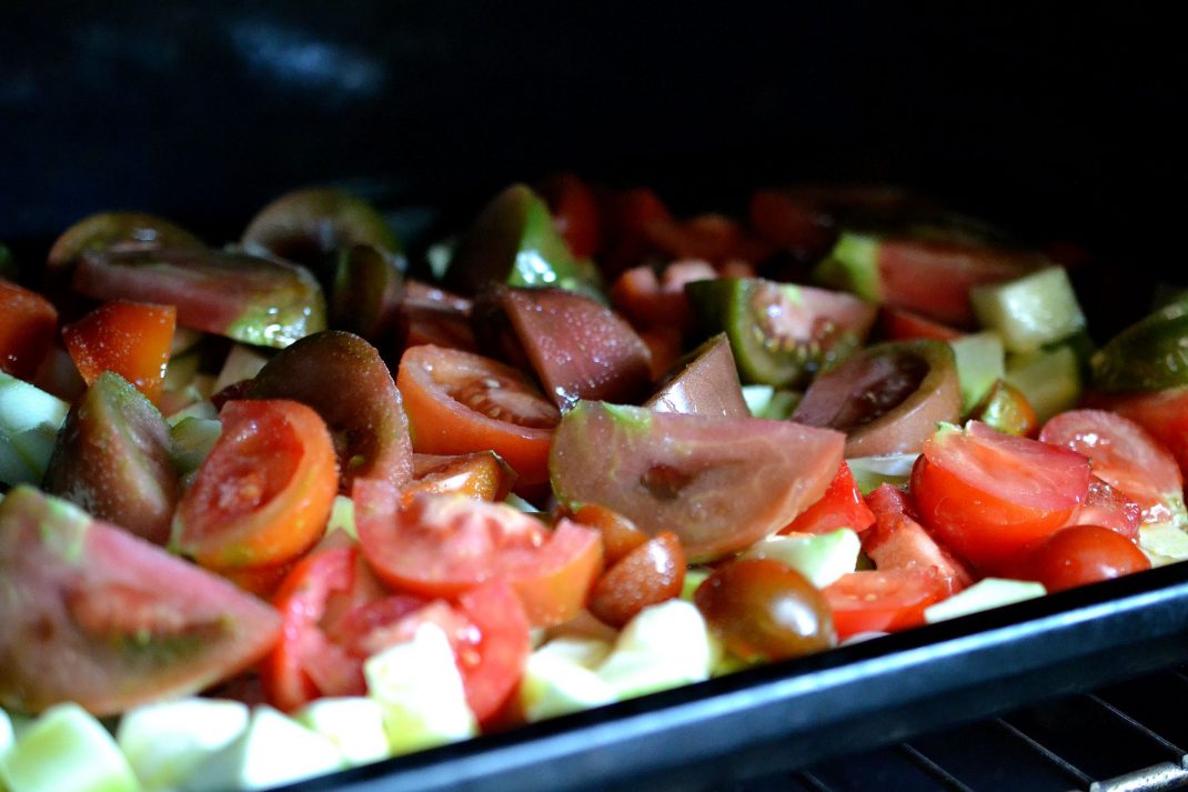 Tomater och andra grönsaker på en plåt i ugnen. 