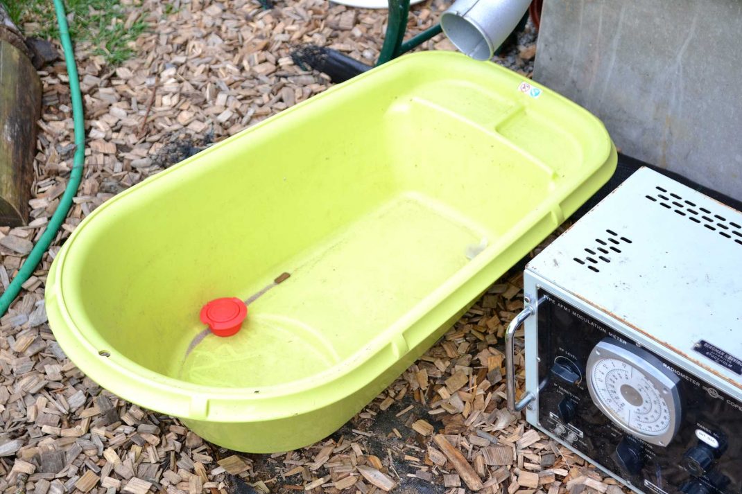 En badbalja under ett stuprör, a plastic tub under the drainpipe.
