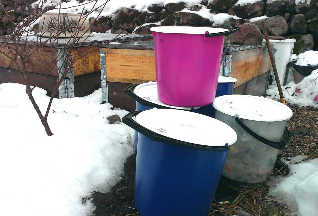 Hinkar med bokashi står ute vid en pallkrage. Storing bokashi, buckets with bokashi compost next to a pallet collar bed.