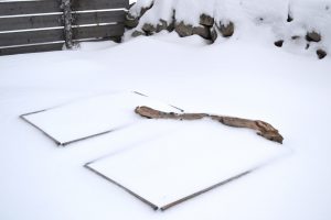 Två pallkragar täcka av snö. En stor gren ligger ovanpå.