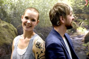Sara Bäckmo och Johannes Wätterbäck, fotograferade på Trädgårdsmässan i Stockholm 2017 framför en fondvägg som visar en naturmiljö.