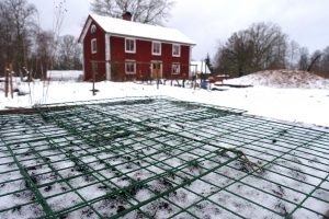 Vintrig trädgård med snö och en odlingslåda täckt med kompostgaller i förgrunden.