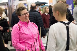 En kvinna i rosa tröja pratar glatt med Sara som står med ryggen till.