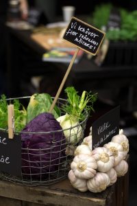 ett stilleben av rödkål, fänkål, vitlök med mera och en skylt med texten "Vi behöver fler trädgårdsmästare!"