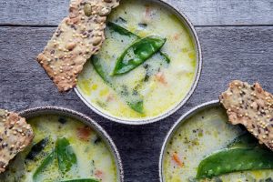 Tre skålar med guldgul, skummande soppa toppad av sockerärt. Vid sidan ligger ett krispigt fröknäckebröd.