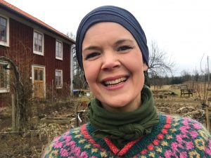 Sara Bäckmo i fägglad tröja ute i köksträdgården.