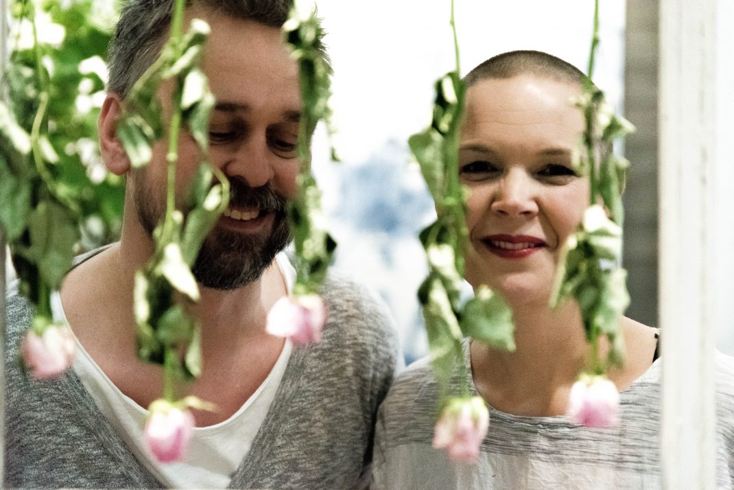 Johannes och Sara står bakom en skir garden av rosa blommor.