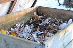 En pallkrage är full av halvförmultna löv och det syns ett tunt lager med snö på marken.