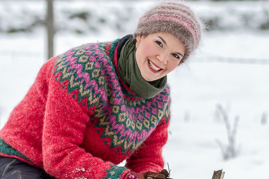 Sara Bäckmo i färgglad tröja och stort leende i snön.