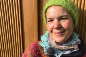 Bild på Sara mot en mörkt senapsgul trädörr.