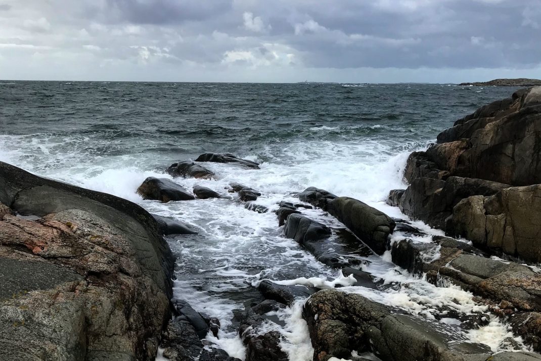En bild på havet som slungar upp skummande vågor mot klipporna. 