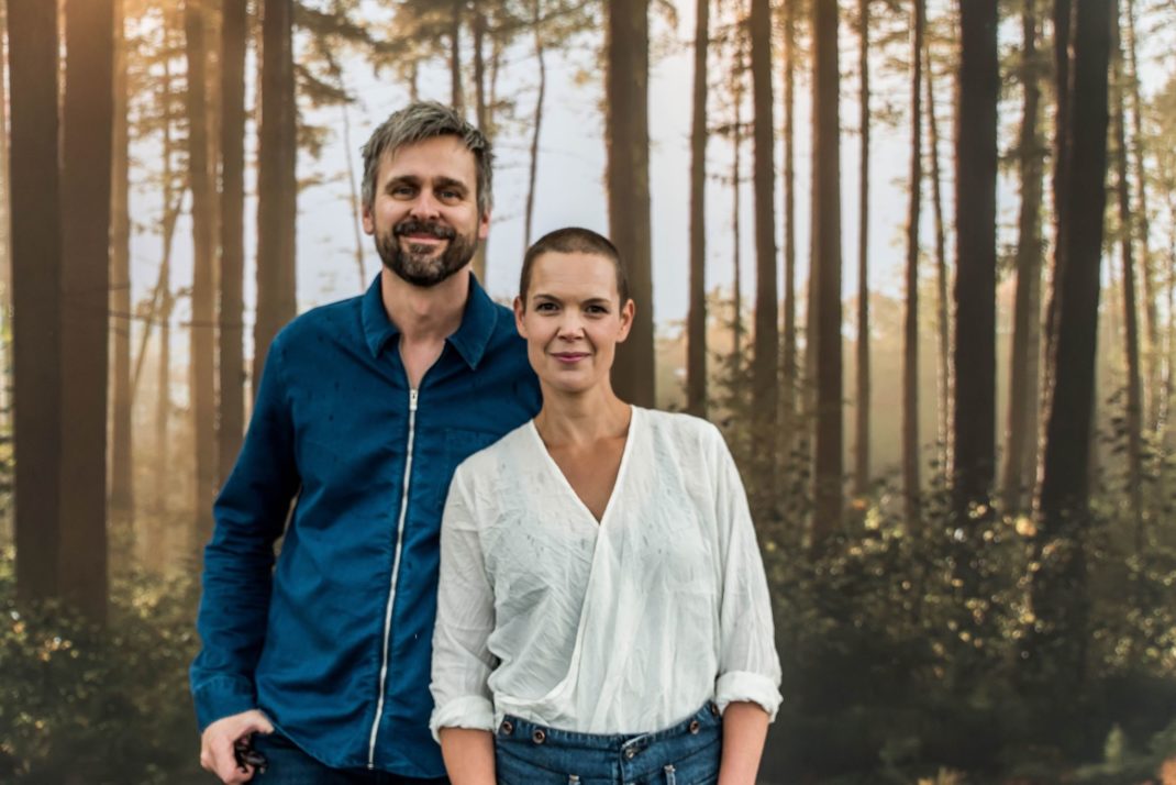 Sara och Johannes står framför en ljus bokskog och tittar in i kameran.