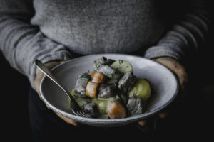 En perosn i grå tröja håller en tallrik med dillkött.