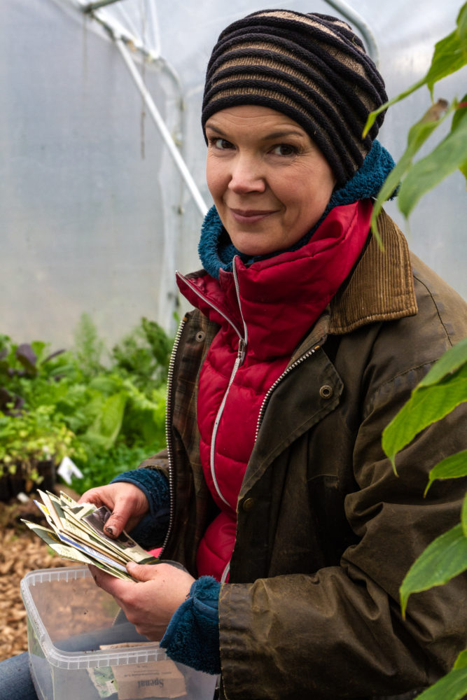 Sara i röd tröja tittar in i kameran i växthuset.
