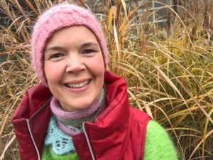 Sara sitter framför fint gyllene, högt gräs.