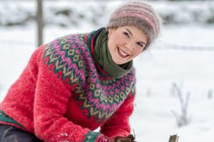Sara Bäckmo i snön med en vackert mönstrad tröja i rosa grundfärg.