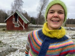 Sara med ett stort leende framför vintergrå trädgård.