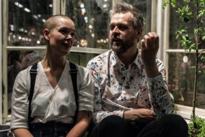 Sara och Johannes sitter framför ett växthus och pratar.