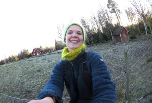 Sara Bäckmo står i trädgården med beteshagen bakom sig, vinter.