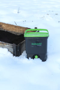 Bokashi bredvid en pallkrage med jord.