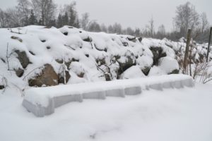 Ett snötäckt landskap med stenmur och ett land som anas under snön.
