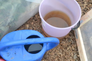 En vattenkanna och en hink med kiss till varmbänken av ull.