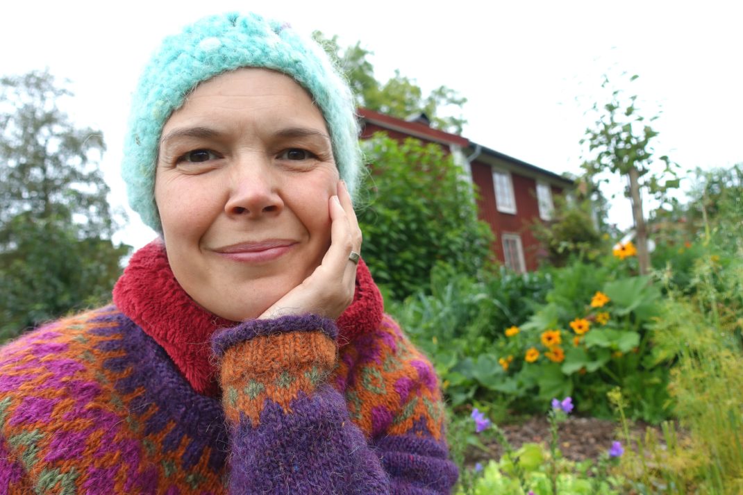 Sara Bäckmo sitter i en sensommarköksträdgård. 