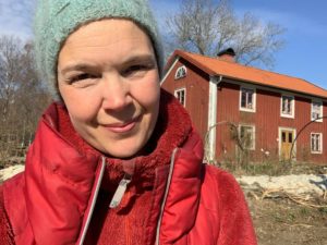 Sara med röd jacka i ett soligt Skillnadens Trädgård.