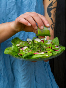 En fin sallad med rädisa och spenat, som Sara häller dressing över.