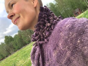 Sara står upp och tittar ut över kohagen och visar tröjans ok.