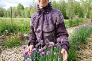 Sara sitter vid blommande lila gräslök.