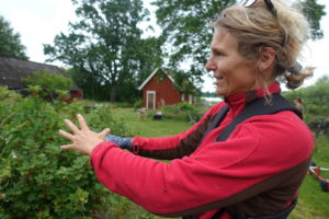 En kvinna i röd fleecetröja står och gestikulerar.