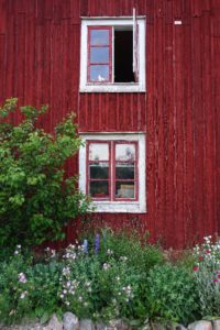 Stående bild på södergaveln med frodiga blommor nedanför.