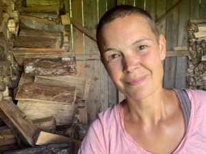 Sara sitter i vedboden med en rosa tröja på sig.
