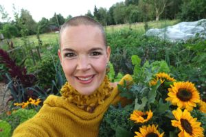 Sara i gul stickad tröja med ett fång solrosor i famnen.