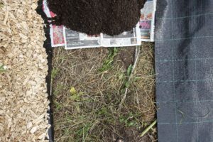 Bild tagen ovanifrån på markduk, träflis, tidningar och jord.