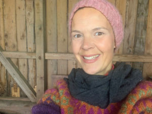 Sara i stickad mössa i vedförrådet.