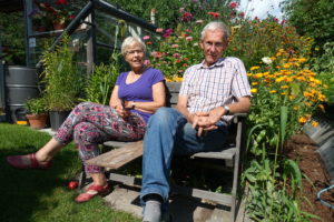Ett äldre par sitter i en blommande trädgård
