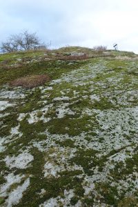 Berghäll med mossa och solur på toppen