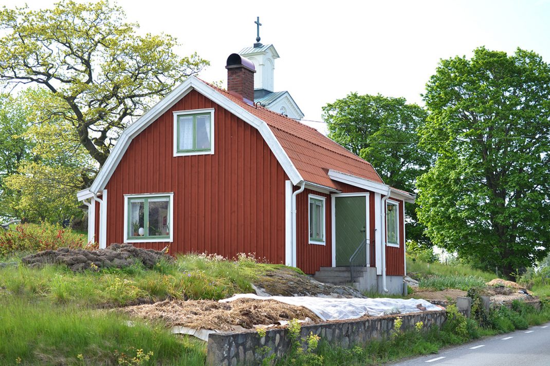 En rött hus på landet med köksträdgård på framsidan