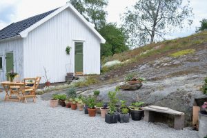 Uteplats vid ett berg med grus och krukor.
