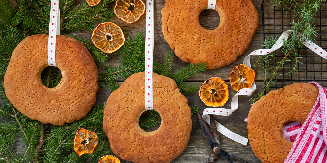 Dopp-i-grytan-bröd hänger i vita band med en fond av granris och torkade apelsinskivor.