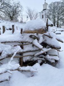 Snön har lagt sig på ett kviststaket.