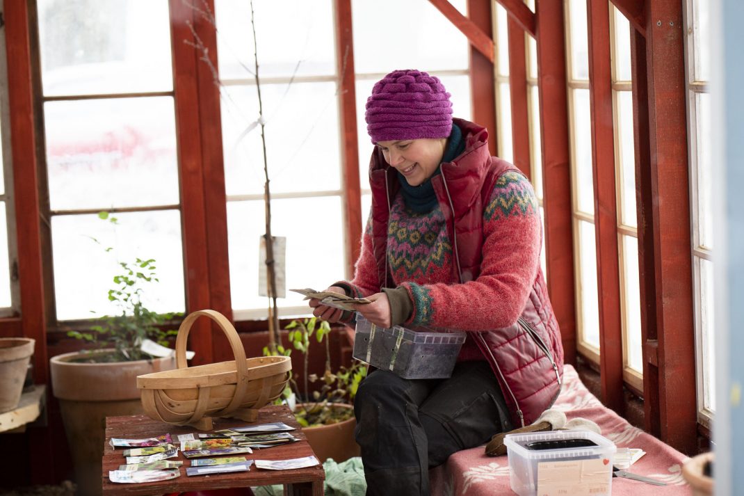 Sara sitter i växthuset och sår.