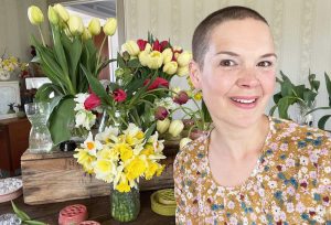 Sara framför ett blomsterhav av gula och röda tulpaner och påskliljor.