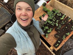 Sara bredvid ett bord av plantor.