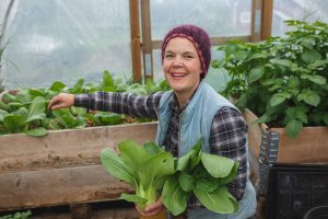 Sara skördar pak choi i växthus