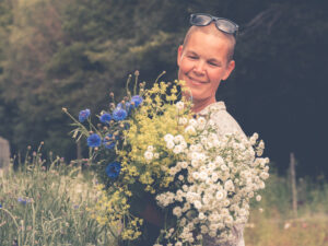 Sara med ett fång sommarblomster av klint, daggkåpa och mattram.