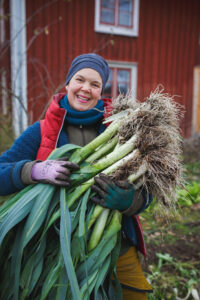 Sara med nyskördade purjolökar som ska sättas i växthus